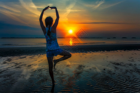 女孩让日出在海边沙滩上晒太阳身体的问候锻炼图片