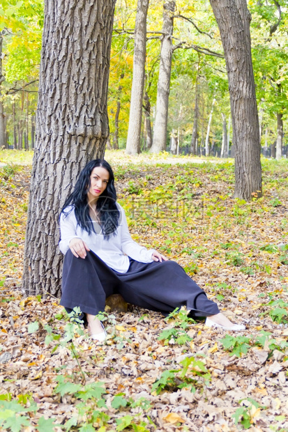 欧洲黑发人坐在秋天公园树下女四十二图片