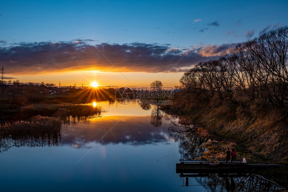 在伊凡诺沃市乌德河岸的两位年轻人享受着美丽的夕阳银行坐着城市图片