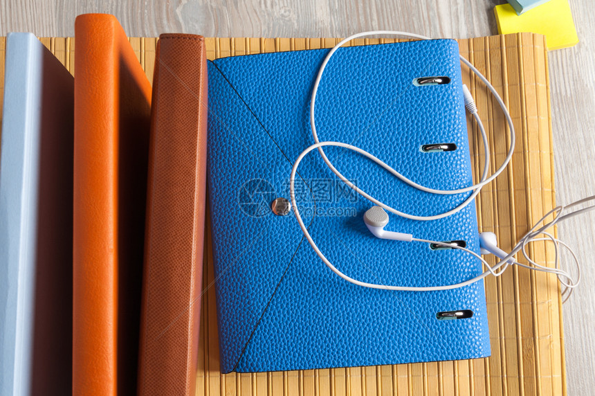 复制皱巴的蓝色笔记本桌上有耳听器和粘黏胶图片