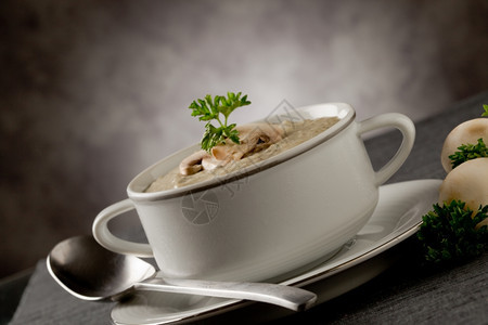 照片美味的蘑菇奶油汤和灰毛巾上的欧斯利牛奶勺子灰色的图片