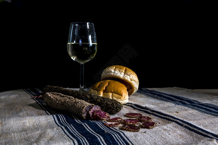 藤蔓仍然有生命桌还一杯白葡萄酒各种干香肠和面粉布上的包带蓝色条纹食物图片