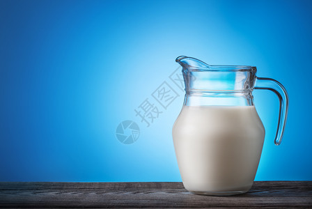 一种产品蓝色的在木桌上加牛奶的果汁和蓝色背景的奶汁在木桌上加牛奶的果汁图片
