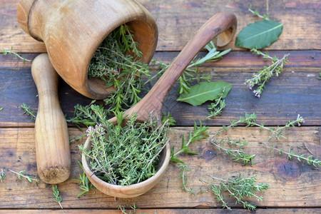 砂浆绿色自然木制勺子中的芳香药草和木制桌上的迫击图片