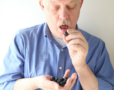 素食主义者正面水平的一个年长男人边吃蓝莓拿着小块图片