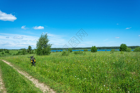 一种在阳光明媚的夏日在田野公路和一条大河外的边骑着旅游自行车夏天晴图片