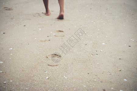 松弛年轻女人赤脚在海滩上走印水图片