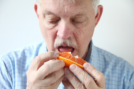 一个老人吃切片橙子正面低脂水平的图片