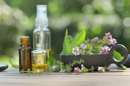关心松弛瓶子桌上和绿背景的香药草花和瓶装基本油花图片