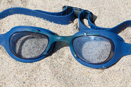 海滩沙上的蓝泳护目镜运动带子保护图片