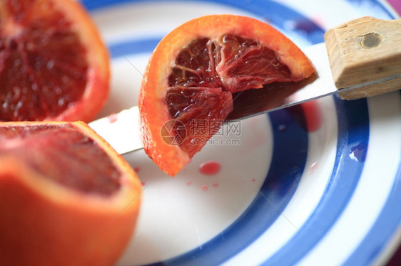 一种柑橘血橙和切片断躺在一把刀子上蓝领的盘子上吃图片