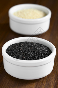 食物味道黑色的小碗中芝麻种子和白与天然光相照选择焦点在黑种子中间的焦点图片