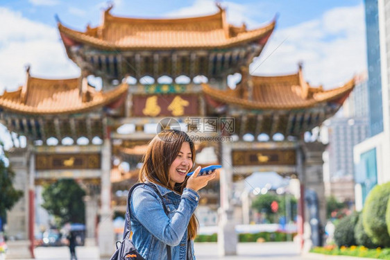 亚洲人使用智能手机作为语音指挥记录器的亚洲旅行妇女在昆明金比广场旅游和著名地点和里程碑式概念旅行时进翻译亚洲旅妇女利用智能移动电图片