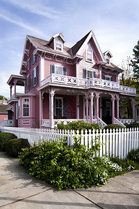 粉色的经过美丽粉红色维多利亚式房子有门廊和阳台四周围着白色的栅栏采摘图片