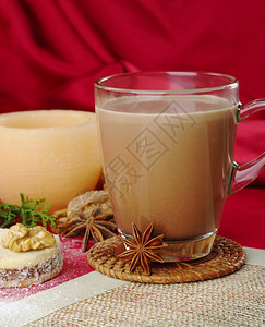 假期圣诞节牛奶热巧克力在玻璃杯中有香肠饼干和蜡烛背景有选择焦点重放在杯子上图片