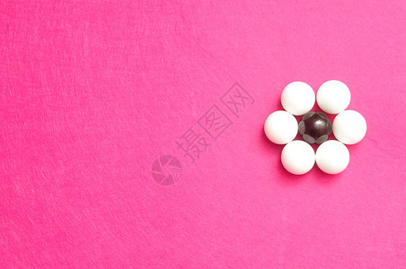 象征一种圆形的以粉红背景孤立的花朵形状包装白球和黑图片