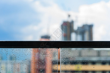 阳台城市城市下雨旅行玻璃阳台雨天和蓝色空背景下建筑的雨滴背景