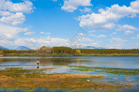 渔夫景观人类在湖岸边捕鱼用泊森林蓝天和云彩从陆地上捕鱼抓住图片