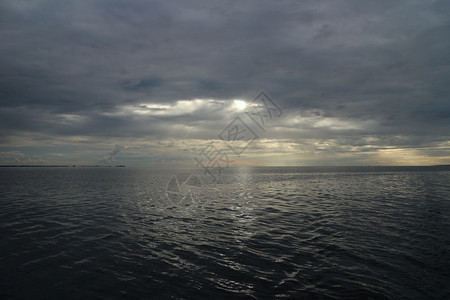 天气一种海面上束光破开黑暗的暴风云海景笼罩着深厚的乌云海浪图片