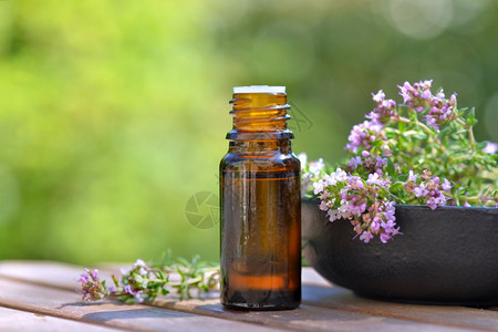 绿色背景桌上的香油和芳药草花瓶装基本油和朵一种关心松弛图片