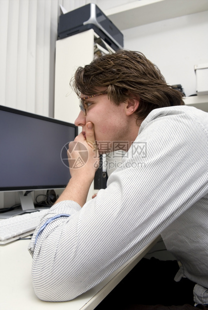 休息一个设计师在电脑屏幕上手肘在桌子下巴他的手里躺着看深孔的花中心集盯着图片