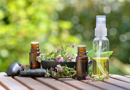 治疗桌上的花瓶和香药草以及绿本底的几瓶必要油和香药草花可以接受和绿色本底的花瓶一种自然图片