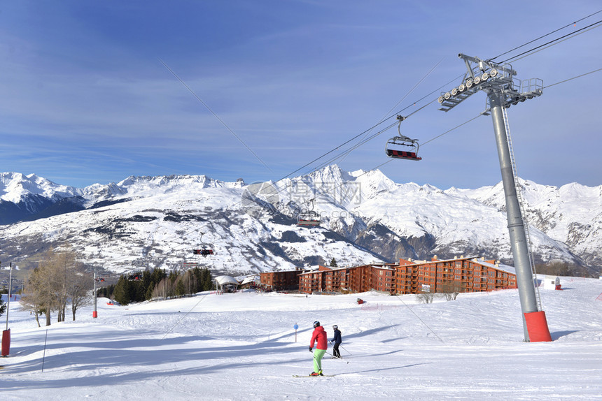 阿尔卑斯山度假胜地的雪坡和蓝色天空下的缆车图片