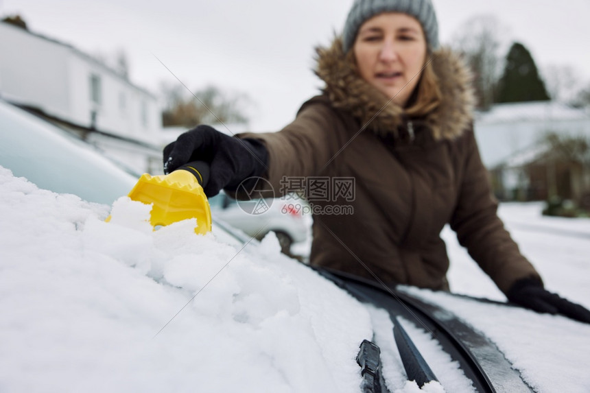 女在冬季清雪中从风屏幕上扫出人们早晨刮刀图片