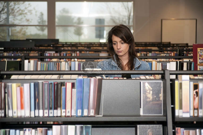 单身的精装书年轻女在公共图书馆用几本架搜索籍的藏室20多岁图片