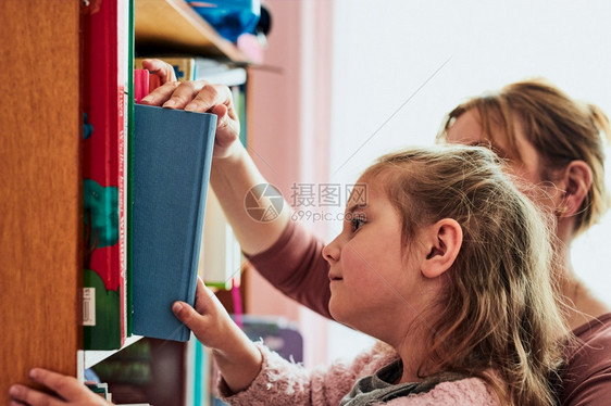 教育学龄前小女孩选择一本书读孩子由母亲从书架上取给孩子看阅读学龄前儿童图片