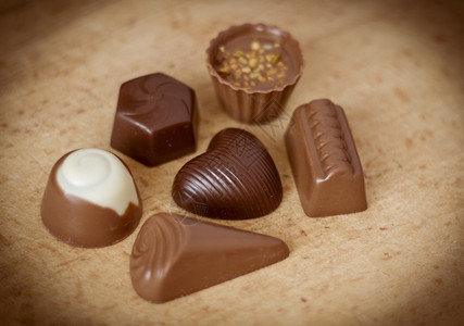 巧克力糖以心脏的形状与木制背景的巧克力糖果好吃棕色的礼物图片