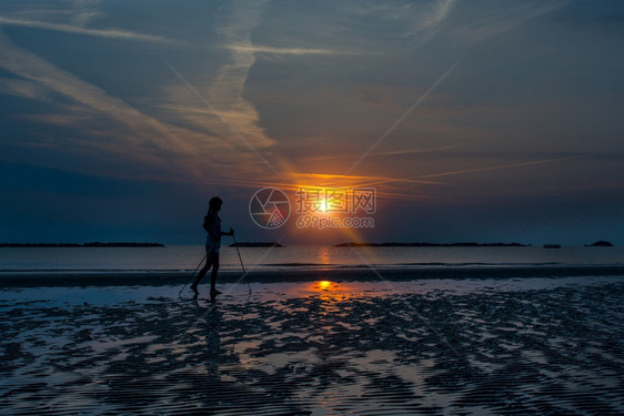 低的身体在日出时海滩上散步的北欧女孩独自一人体操图片