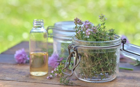 将玻璃罐和油瓶装在花园的一张桌子上安排的瓶中玻璃罐和油一种芳香草本植物图片