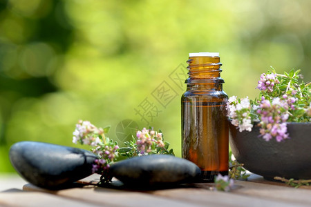 美丽芳香桌上和绿色背景的一瓶精油和香草花鹅卵石桌上绿色背景的精油和香草花瓶健康图片