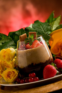 草莓布丁反射在玫瑰背景前有浆果的巧克力栗子甜瓜一种背景