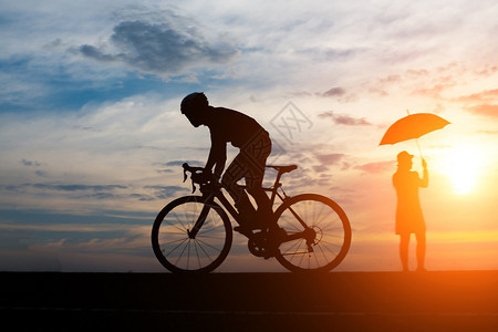 海滩夏天年轻人在日落背景下骑自行车术图片