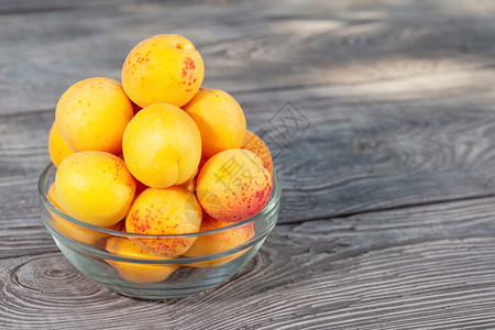 甜点木板上一个玻璃碗中的黄杏子木板上一个玻璃碗中的黄色杏子水果维他命图片