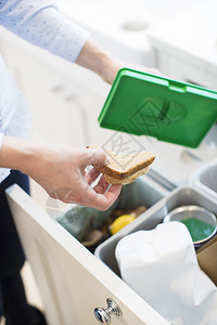 投掷白种人女士近距离将食品废物放入厨房的垃圾桶回收背景图片