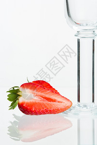 红色的狭缝粉碎草莓和空的闪光葡萄酒杯有反光白色背景颜图片