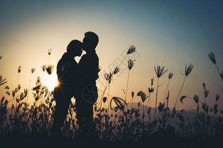 吻假期家庭情侣在日落时的爱情剪影图片
