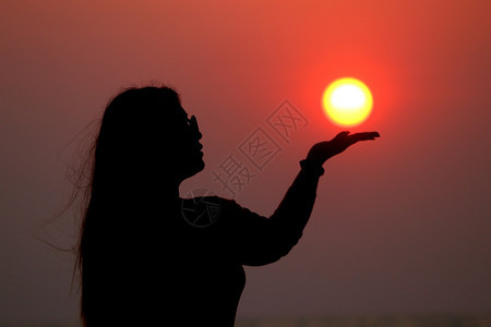 女士阳光太在手上日出时握太阳的脚影图片