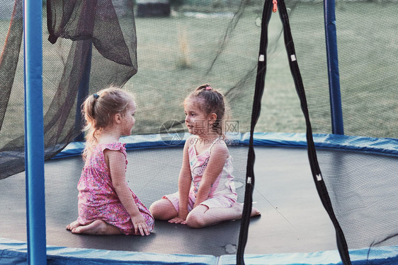 在蹦床上玩耍的两个可爱小女孩图片