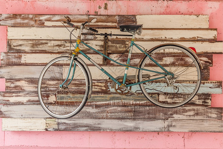 粉色的旧自行车挂在木板背景上白色的运动图片
