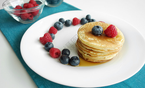 山莓美国人早餐背景和一堆煎饼蓝莓草和糖浆的早餐果图片