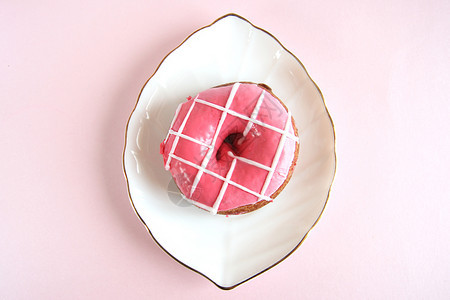 盘子白板上条纹状的明亮粉红甜圈其形式为叶子金涂在粉红色背景空间上明亮的小吃图片