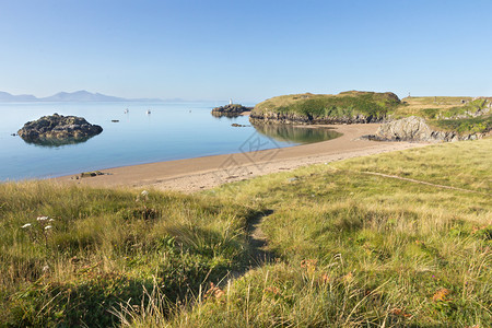 Llanddwyn岛海滩Anglesey和Llindwyn岛海滩与背景中的Ihghhouse和远处的Llyn半岛安格尔西夏天股票图片