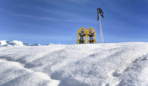 蓝色天空下山顶的雪鞋下的棍子寒冷图片