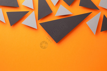 明亮的橙色纸张背景的黑三角和灰色形摘要构成文字空间为从上方查看抽象的作品图片