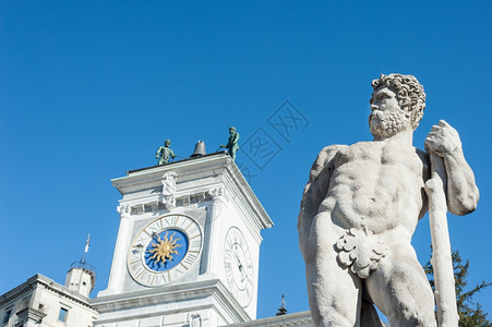 天空在意大利乌丁自由广场教堂的钟塔具有背景的Caco雕像乌迪内图片