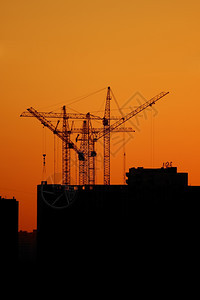 行业住房高的日落时建造起重机组月光对橙色天空图片